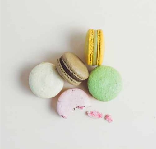 5 Macarons, each of a different color: white, coffee, yellow, green, pink