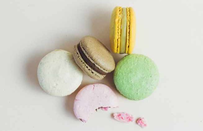 5 Macarons, each of a different color: white, coffee, yellow, green, pink