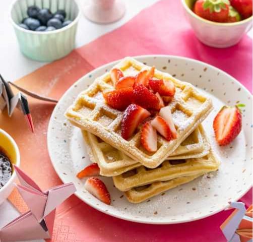 waffle in a plate with strawberries on top