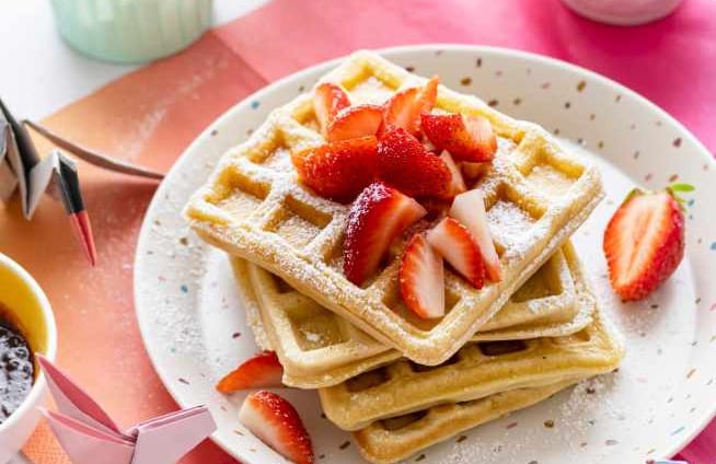 waffle in a plate with strawberries on top